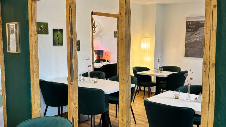 Ein modernes Restaurant mit grünen Wänden und stilvollen Möbeln. Die Tische sind schön gedeckt und es gibt eine gemütliche Atmosphäre.