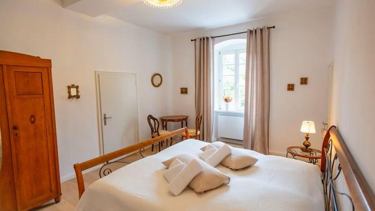 Ein helles Schlafzimmer mit einem großen Bett und einem gemütlichen Holzschrank. Das Fenster sorgt für viel natürliches Licht und eine einladende Atmosphäre.