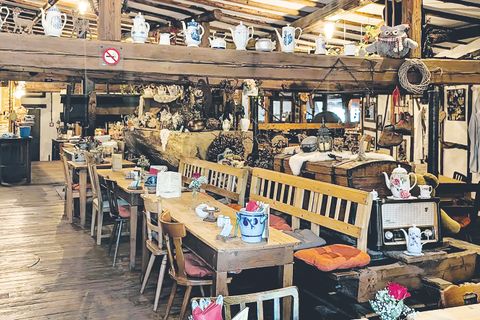 Innenraum des Restaurants mit Holztischen- und Stühlen geschmückt mit alten Teekannen- und Tassen