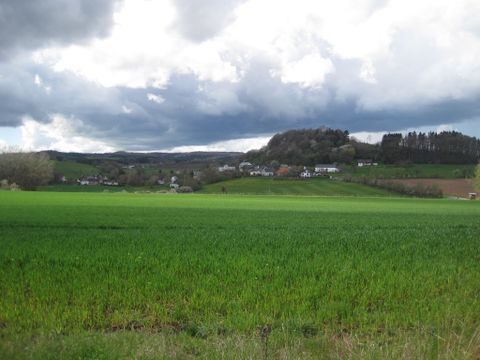 Grüne Wiesen und Hügel unter bewölktem Himmel, Blick auf Basberg.