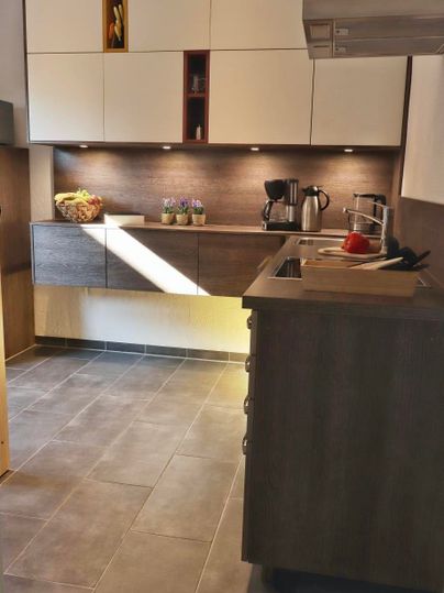 Een moderne keuken met houten en witte kasten. Op het aanrecht staan een koffiemachine en enkele keukengerei.