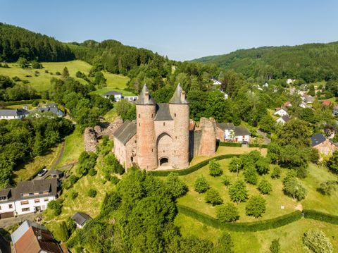 Luftaufnahme der Bertradaburg Mürlenbach mit grüner Landschaft herum