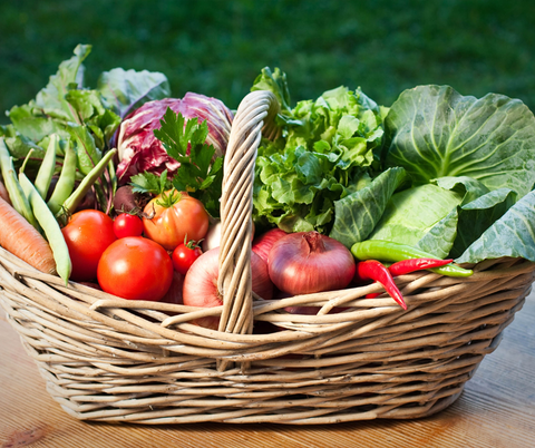 Symbolbild-Auf einem alten Holzbalken steht ein viereckiger, geflochtener Korb. Im Korb  liegen verschiedene Gemüse wie Kohlrabi, rote Beete, Paprika,Zwiebeln, Petersilienwurzel und Tomaten.<br/>Rechts sieht man einen  Kopf Salat, links ein Zweig Pfefferminze.
