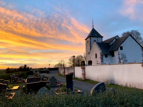 Wehrkirche bei Sonnenuntergang mit Friedhof im Vordergrund.