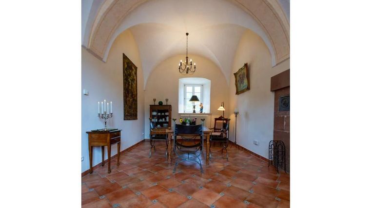 Ein eleganter Essbereich mit einem großen Tisch und Holzstühlen. Die Decke ist gewölbt und der Raum ist freundlich beleuchtet.