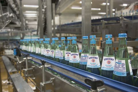 Fließband mit zahlreichen Wasserflaschen der Marke Gerolsteiner und Abfüllanlage.