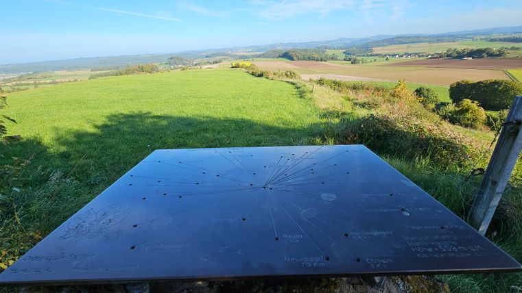 Viewpoint with metal plaque and view of green landscape.