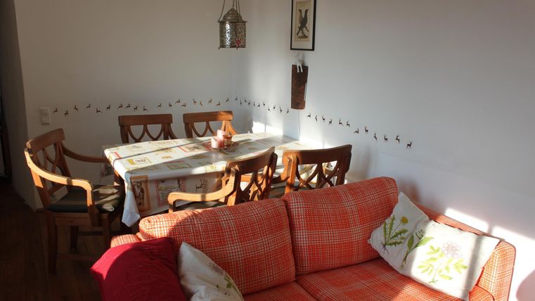 Een uitnodigende woonkamer met een oranje bank en een houten eettafel. De muren zijn versierd met decoratieve elementen.