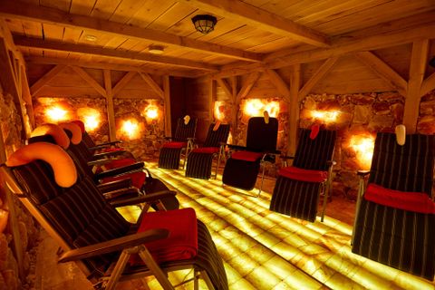 Innenansicht einer Salzgrotte mit Liegestühlen und beleuchteten Wänden.