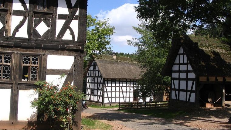 Ein malerisches Dorf mit Fachwerkhäusern und grünem Umfeld. Der Himmel ist klar und die Atmosphäre ist ruhig.