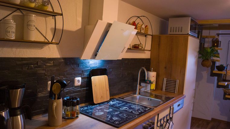Een moderne keuken met houten meubels en stijlvolle planken. De verlichting benadrukt het werkblad en creëert een uitnodigende sfeer.