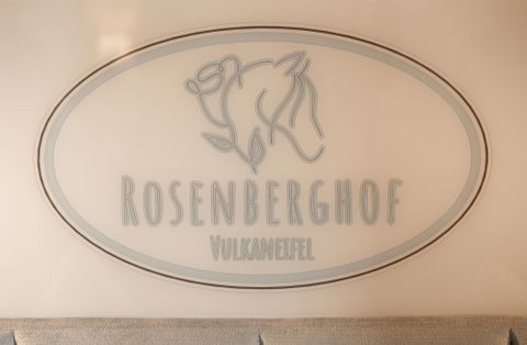 Een bord met de tekst "ROSENBERGHOF" en de toevoeging "VulkanEifel". Het ontwerp toont een gestileerde weergave van een dier.
