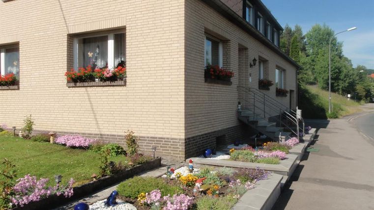 Ein gemütliches Haus mit einem gepflegten Garten. Bunte Blumen und dekorative Elemente verschönern den Außenbereich.
