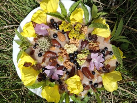 Een mooi opgediende schotel met een selectie van noten, gedroogd fruit en eetbare bloemen. De frisse gele tinten en kleurrijke bloemen geven het gerecht een aantrekkelijke uitstraling.