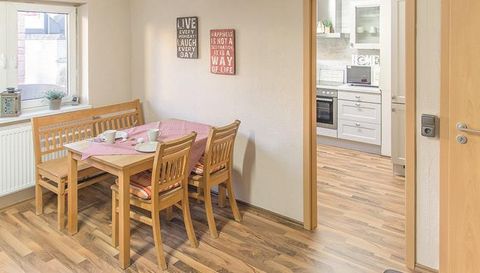 Een lichte keuken met een gezellige eetruimte. De tafel is gedekt en er is uitzicht op de aangrenzende ruimte.