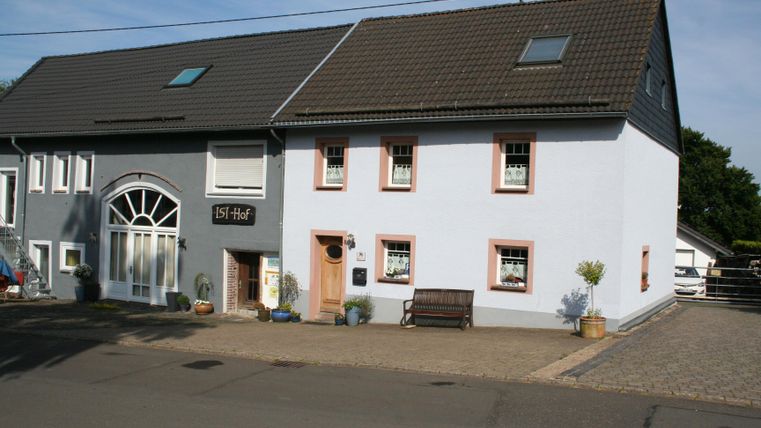 Een charmant huis in lichtblauwe kleur naast een grijs gebouw. De straat is rustig en uitnodigend.