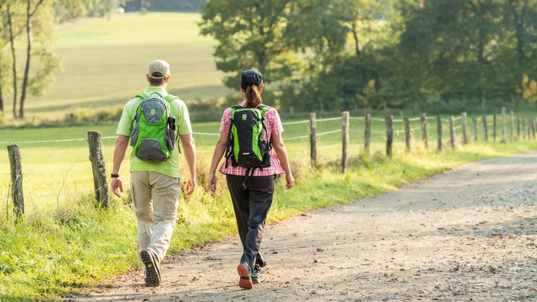 Zwei Wanderer auf einem ländlichen Weg in der Eifel.