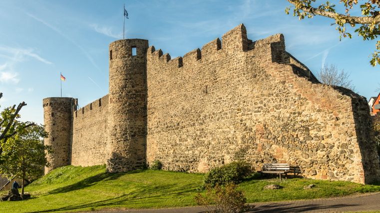 Historische Stadtmauer mit Türmen und Fahnen in Hillesheim bei sonnigem Wetter.