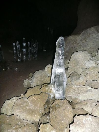 Ein Eiszapfen, der von unten aus einem Felsen nach oben ragt. Im Hintergrund sind weitere EIszapfen zu erkennen.