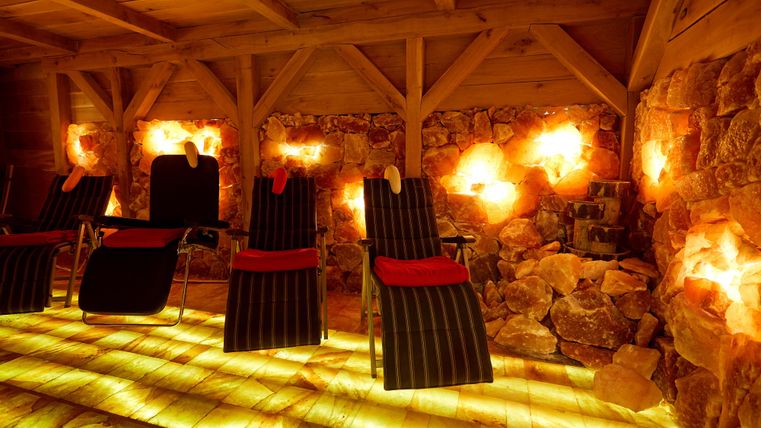 Salzgrotte mit Liegestühlen, umgeben von beleuchteten Salzsteinen und Holzbalken, schafft eine entspannende Atmosphäre.
