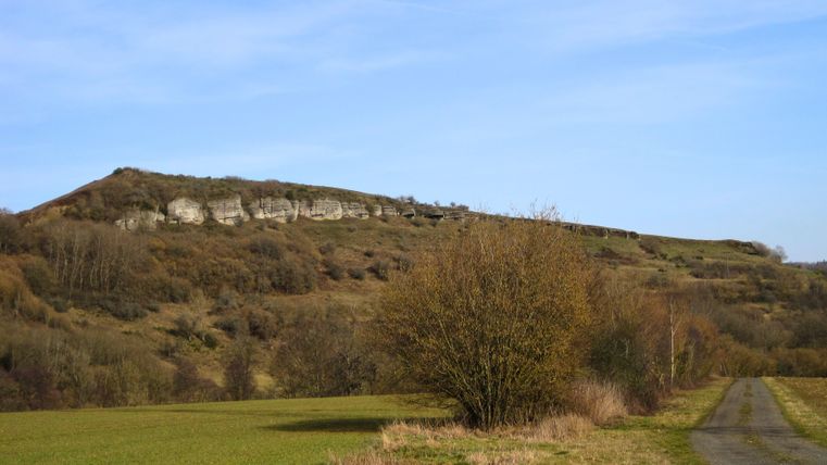 Landschaft mit Hügel und Felsen unter blauem Himmel.