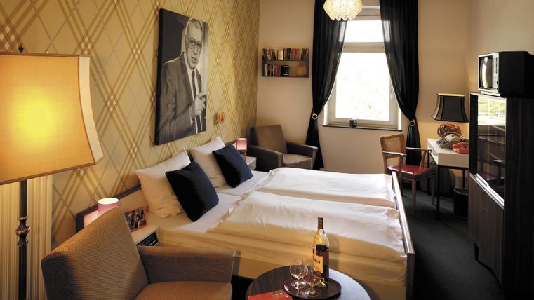 Une chambre d'hôtel confortable avec deux lits, un bureau et un coin salon. Les murs sont décorés et une image est accrochée derrière les lits.