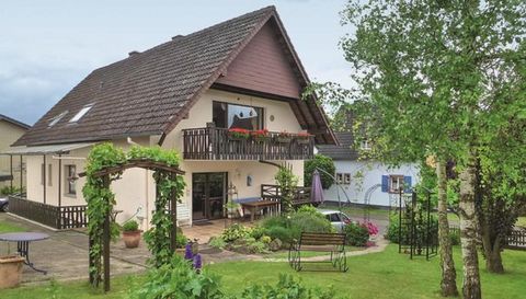 Ein schönes Haus mit einem Balkon und einem gepflegten Garten. Umgeben von Bäumen und Blumen wirkt es einladend und freundlich.