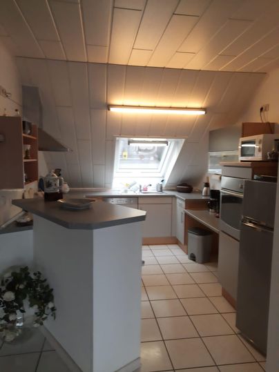 Eine moderne Küche mit weißen Schränken und Geräten. Das Fenster sorgt für viel natürliches Licht.