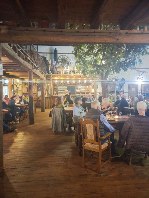 Zahlreiche Personen sitzen an Tischen in einem großen Restaurantraum.