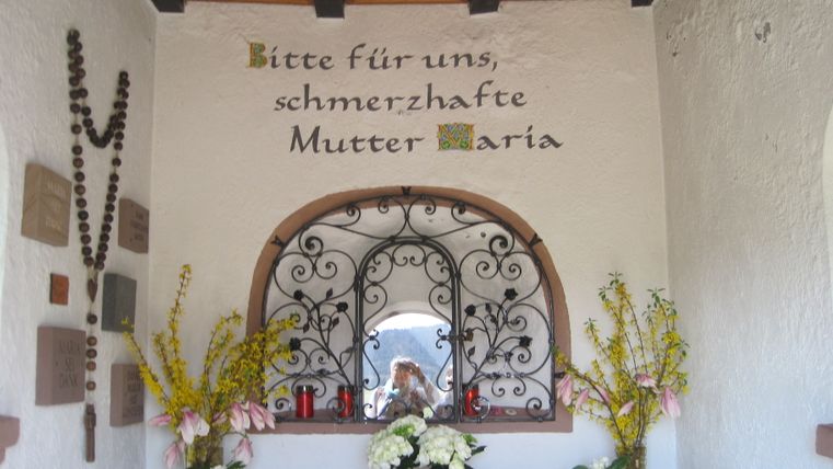 Kleine kapel met bloemen en de woorden 'Bid voor ons, bedroefde Moeder Maria'.