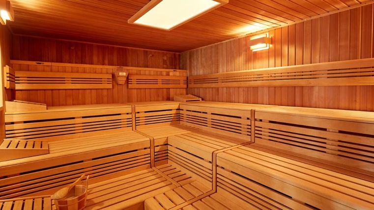 Eine komfortable Sauna mit Holzbänken und warmem Licht. Der Raum bietet eine entspannende Atmosphäre für Erholung und Wellness.