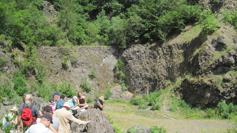 Group of people sitting on rocks in a green, rocky landscape.