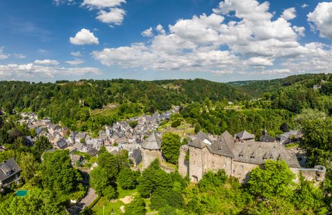 Panoramablick auf Monschau mit Burg und grüner Landschaft.