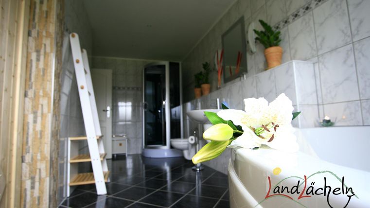 Ein modernes Badezimmer mit einer Badewanne und einer Dusche. Pflanzen in Töpfen verleihen dem Raum eine frische Atmosphäre.