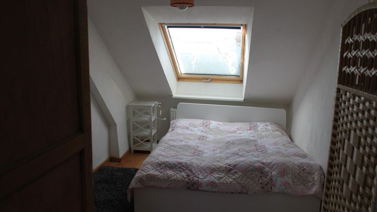 Een gezellig slaapkamer met een tweepersoonsbed en een dakraam. De ruimte heeft een rustige sfeer met minimalistische inrichting.