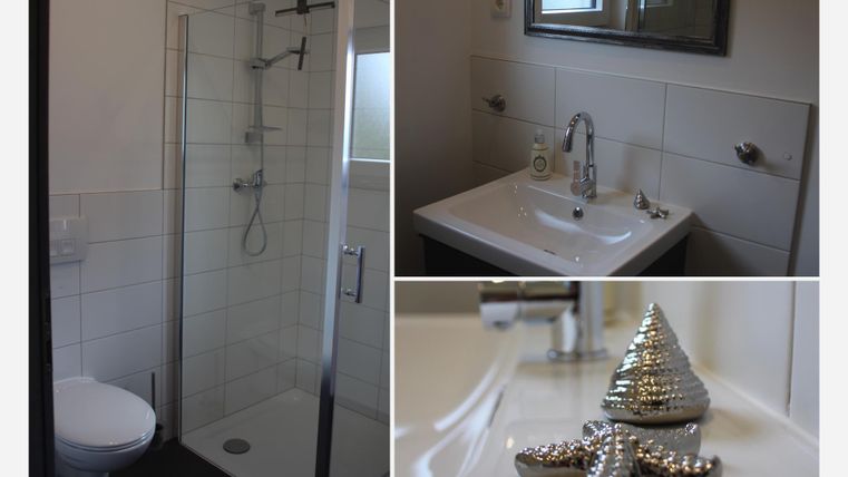 Ein modernes Badezimmer mit einer Duschkabine, einem Waschbecken und eleganten Armaturen. Dekorative Elemente wie ein glänzender Stern und eine kleine Figur sind ebenfalls sichtbar.