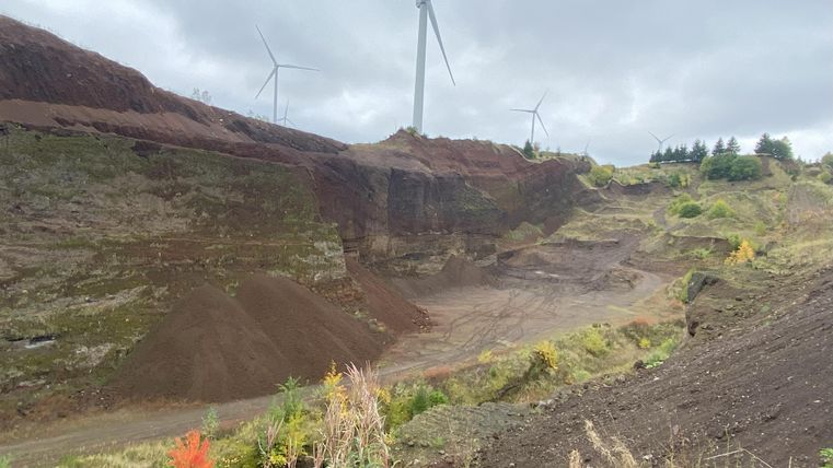 Ici, on a une vue sur le volcan. On voit des collines légèrement couvertes de végétation. Le ciel est nuageux.