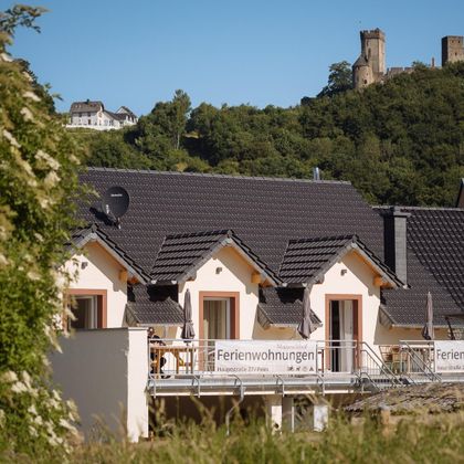 Eine moderne Ferienwohnung mit einem schönen Ausblick auf eine nahegelegene Burg. Die Umgebung ist grün und einladend.