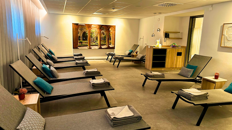 Ein entspannender Wellnessbereich mit Liegen und einer modernen Atmosphäre. Die Wände sind mit beruhigenden Farben gestaltet, und es gibt eine Anrichte mit Annehmlichkeiten.