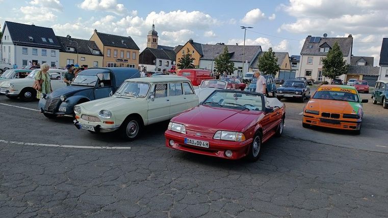 Une voiture ancienne rouge entourée d'autres voitures anciennes