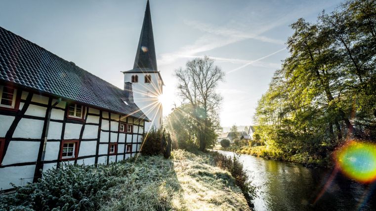Half-timbered house and church in Olef by the river at sunrise.