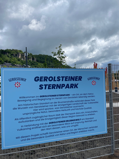 Een blauw bord informeert over het Gerolsteiner Sterrenpark, een plek die beweging, natuurervaringen en de uniekheid van het vulkanische landschap verbindt.
