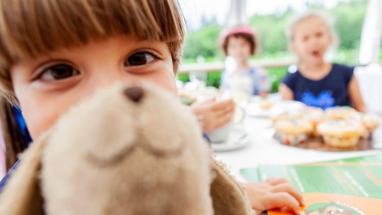 Kind, mit Plüschtier, das nah in die Kamera schaut