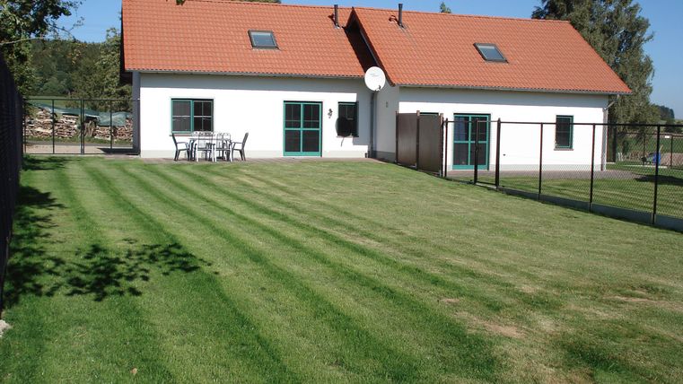 Een modern huis met een rood dak en grote ramen. De tuin is goed onderhouden met versgemaaid gras.