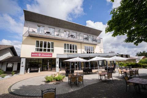Un hôtel moderne avec un espace extérieur accueillant. Il y a des tables et des parasols pour offrir aux clients un endroit confortable pour se détendre.