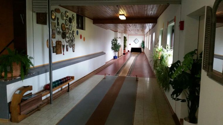 Innenansicht einer Kegelbahn mit Pflanzen und Dekoration an den Wänden.