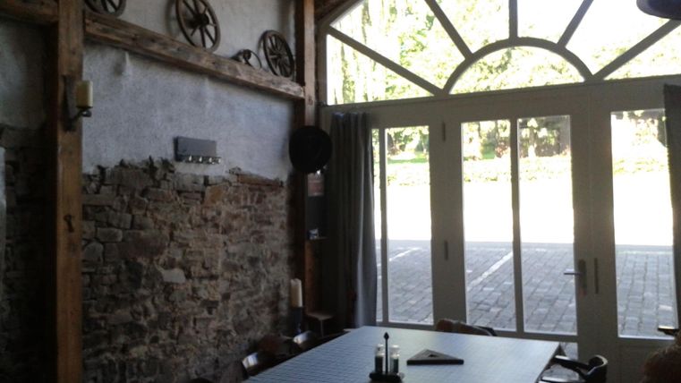 Een gezellige kamer met rustieke flair en grote ramen. Heldere muren en een tafel in het midden nodigen uit om te verblijven.
