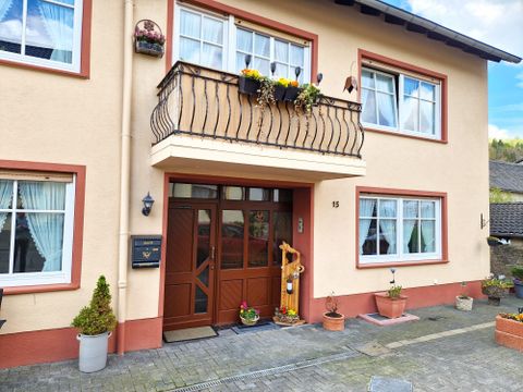 Une maison moderne avec une entrée accueillante. Le balcon est décoré de fleurs et le chemin est orné de pots.