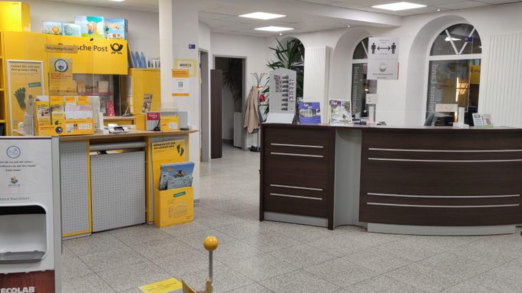 Innenansicht der Touristinfo Hillesheim mit Postschalter, Broschüren und Desinfektionsmittelspender.