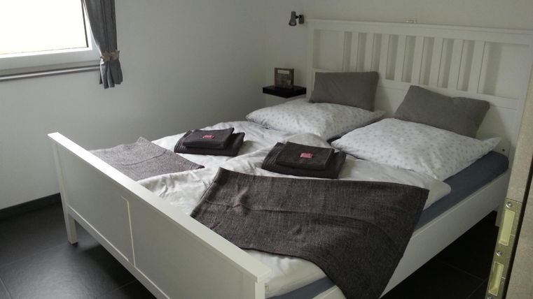 Ein modern eingerichtetes Schlafzimmer mit einem weißen Doppelbett. Frische Bettwäsche und Handtücher liegen ordentlich bereit.